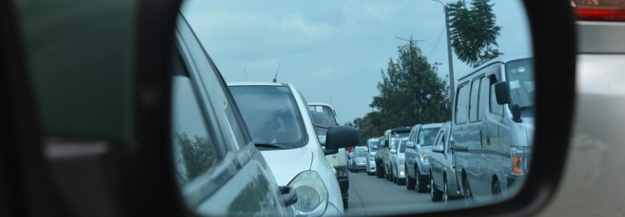A person driving a car, with insurance policy documents and a vehicle key nearby.