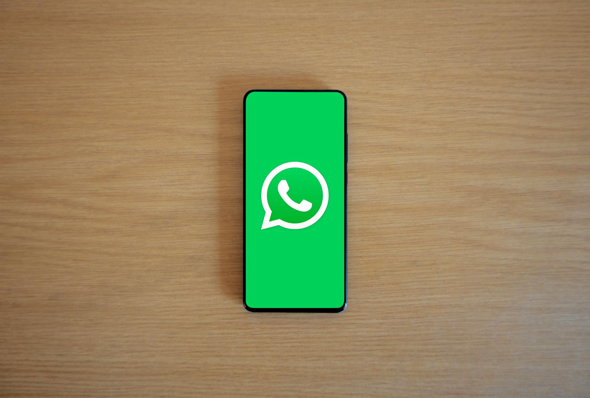 A smartphone displaying a WhatsApp chat for motor insurance, with keys and a car key fob nearby.